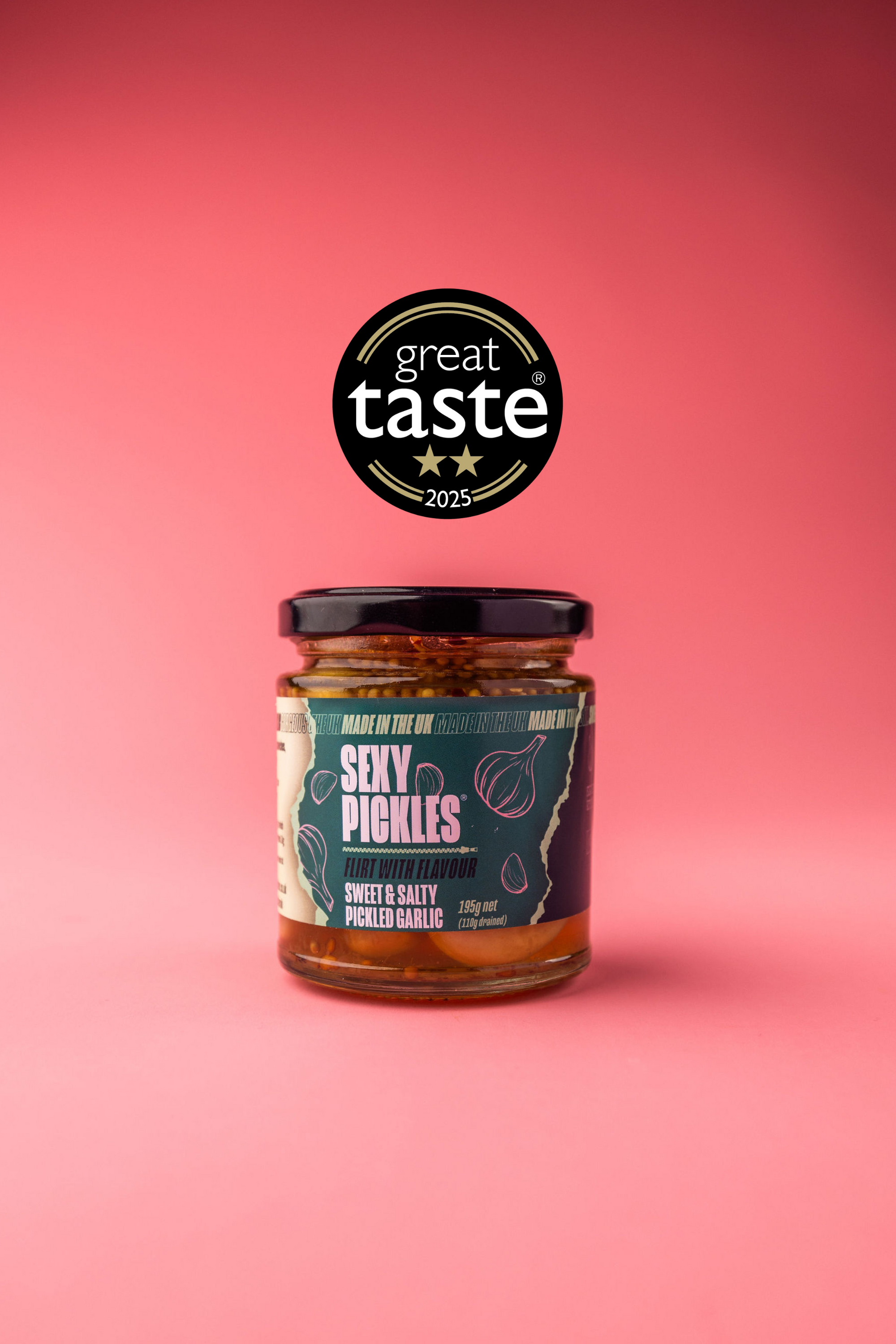 Jar of pickled garlic with a 'Great Taste' award on a pink background