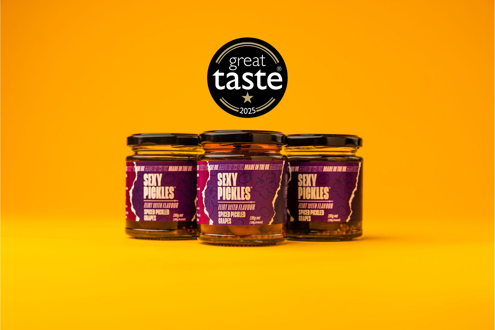 Three jars of 'Sexy Pickles' Pickled Grapes a on a yellow background with 'Great Taste' award logo.